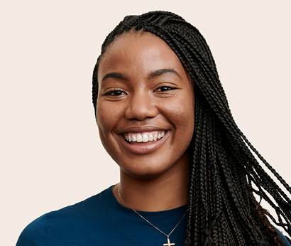 Apple Retail employee with shoulder-length hair and a necklace, smiling at the camera.