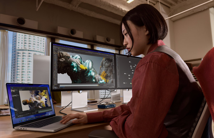 Una persona che lavora in ufficio con un MacBook Pro collegato a uno Studio Display XDR