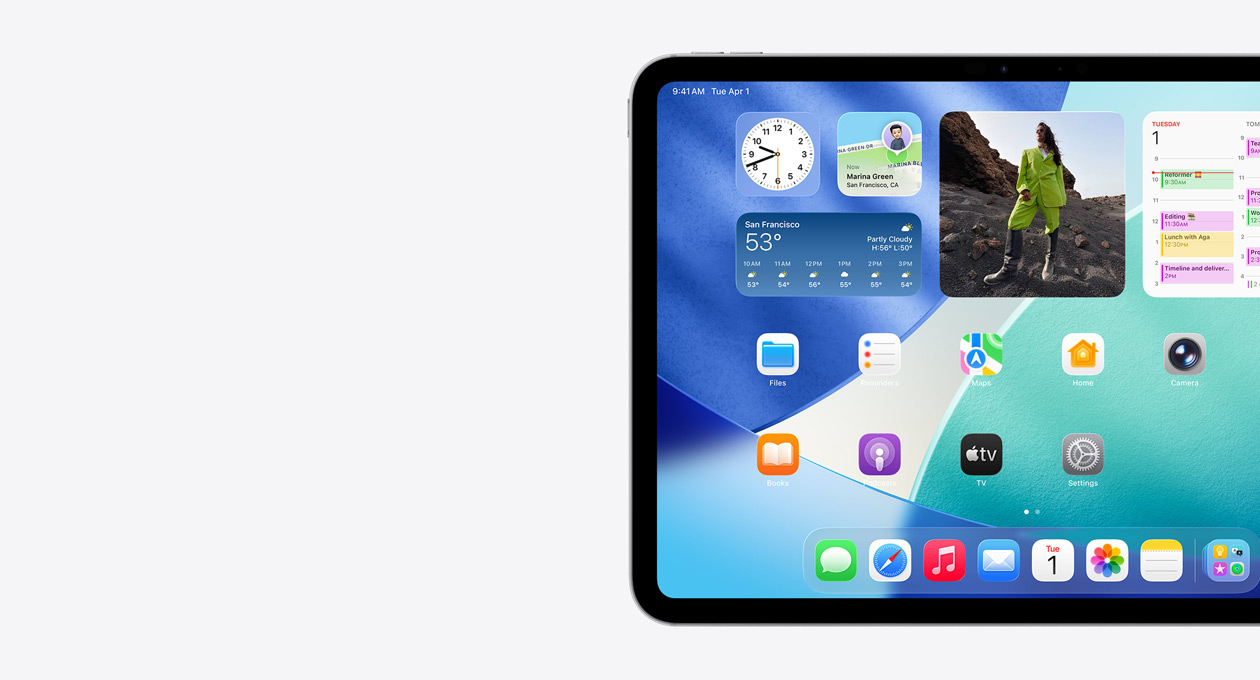 Ein iPad im Querformat, nur die linke Seite des Displays ist zu sehen, darauf der Homescreen mit gestapelten Widgets, einschliesslich transluzenter Uhr mit Liquid Glass Effekt, «Wo ist?» App, Wetter Widget, zwei Reihen kleinerer Apps und des Dock