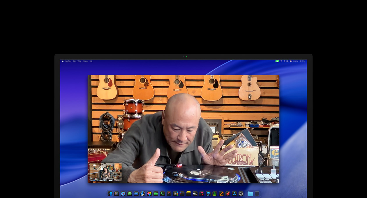 Una persona in un negozio di strumenti musicali sta facendo una videochiamata; mentre si avvicina a un giradischi, rimane al centro dell’inquadratura grazie alla videocamera Center Stage