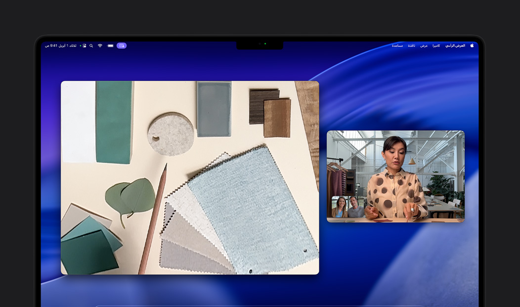 مكالمة فيديو على MacBook Pro لامرأة تستخدم ميزة العرض الرأسي لعرض مساحة عملها المليئة بقطع الأقمشة لشخصين في المكالمة، تتيح لها ميزة العرض الرأسي إظهار مساحة عملها ووجهها في الوقت نفسه