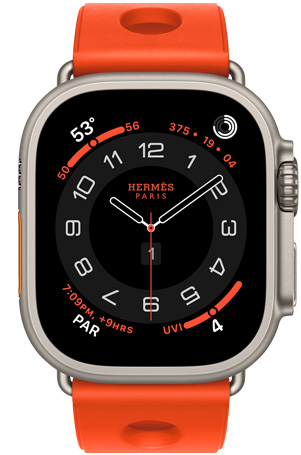 Apple Watch Hermès Ultra 3, Circulaire analog watch face, (hour, minute and second hands, complications: Weather, activity rings, Paris time and UV Index), titanium case, natural color, right side exterior, Digital Crown, raised side button, paired with Scub'H Diving band, orange néon color (bright orange), molded rubber material, circular cutouts centered