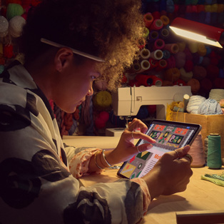 Une personne assise à un bureau se sert de deux doigts pour agrandir le contenu d’une image sur iPad.