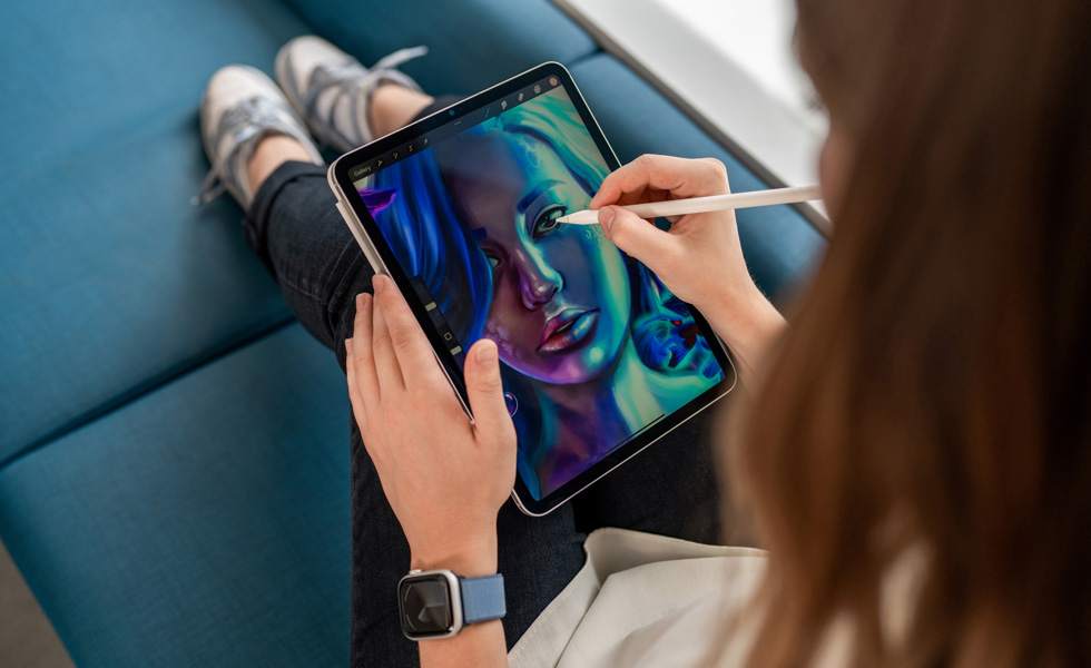 Une étudiante a un iPad sur les genoux et utilise un Apple Pencil pour dessiner dans l’app Procreate
