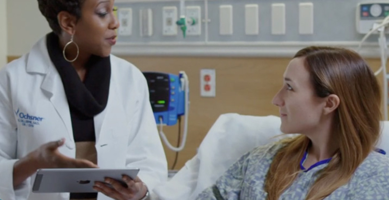 一位醫護人員拿着 iPad 和一位在床上的病人説話。