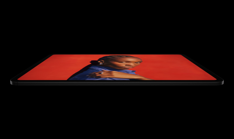 iPad Pro, side exterior, landscape orientation, space black color, rounded corners, black display bezel, display showing an vibrant red screen with a individual posing with their hand on their shoulder wearing a blue shirt
